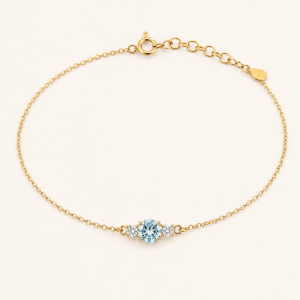 A delicate gold bracelet featuring a luminous aquamarine accented by two sparkling diamonds. Elegant and timeless, designed to add a subtle touch of color and light to the wrist.